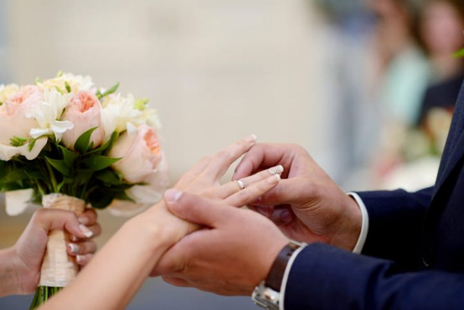мужчина одевает обручальное кольцо женщине